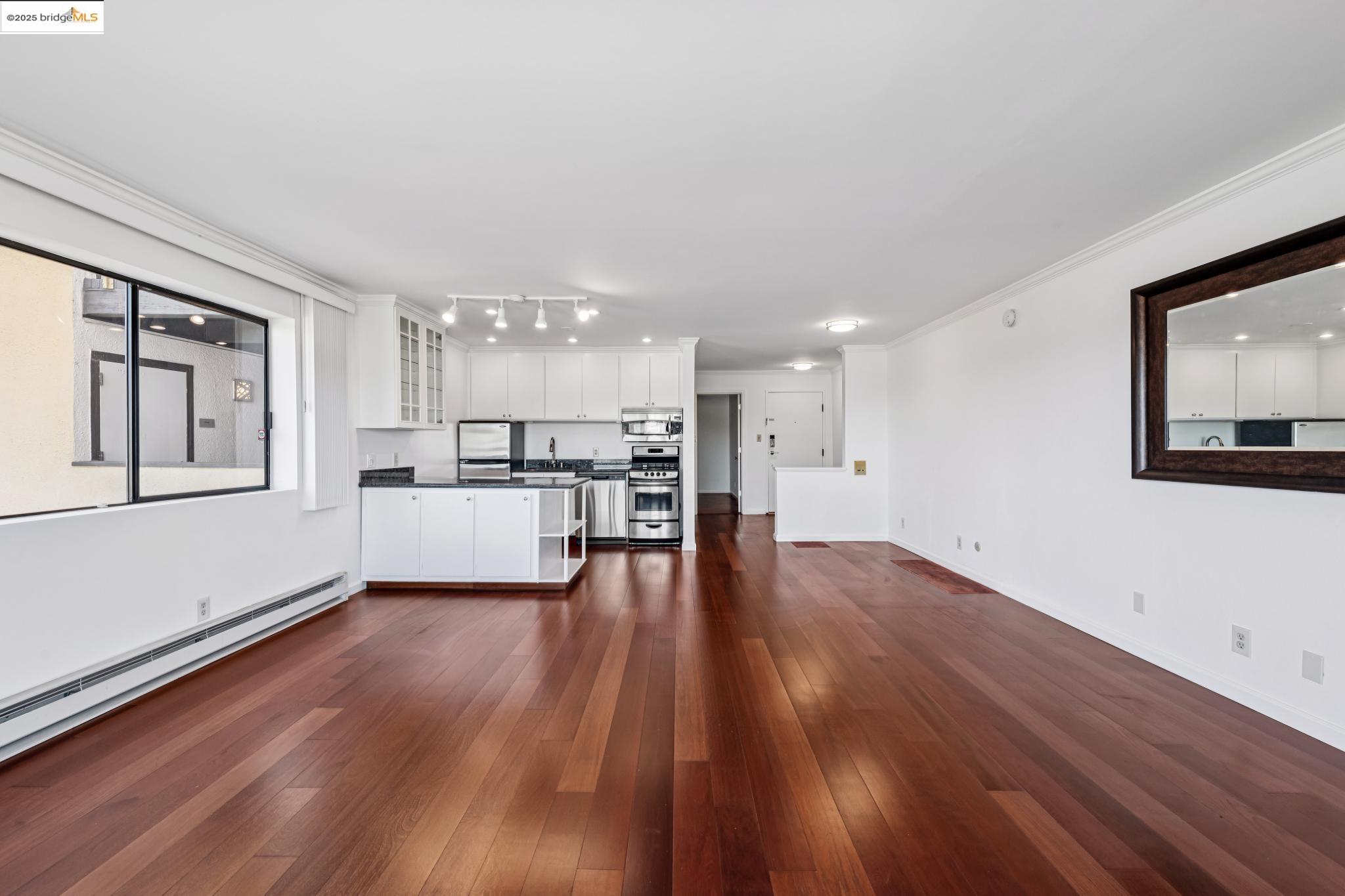 1 Embarcadero, Unit 161 Oakland, CA 94607 - Photo 24 of 31 Unfurnished living room with dark wood-style flooring, crown molding, and baseboard heating
