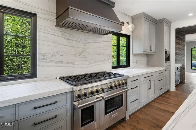 an empty room with wooden floor a ceiling fan and windows