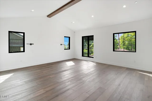 an empty room with wooden floor chandelier and windows