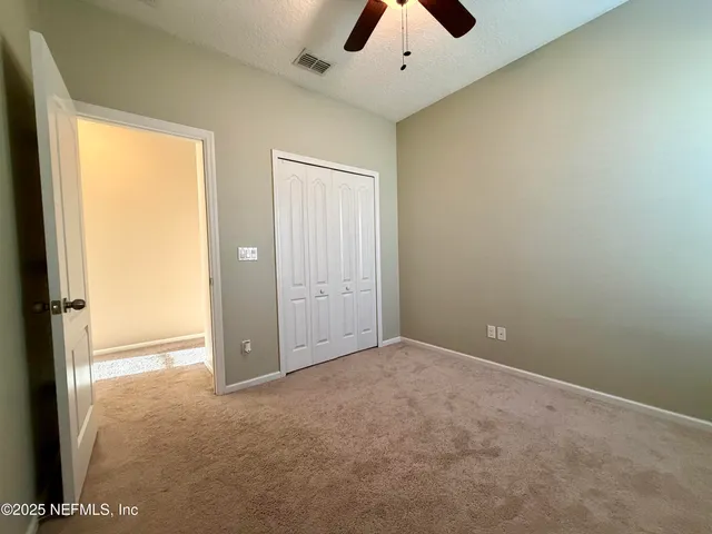 an empty room with chandelier fan and windows