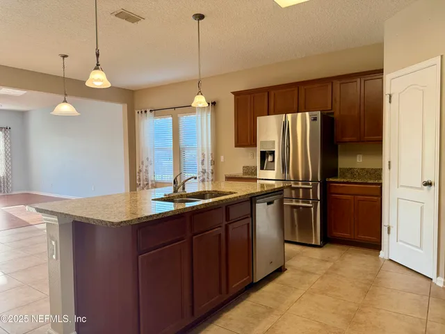 a kitchen with stainless steel appliances granite countertop a refrigerator a sink and a stove
