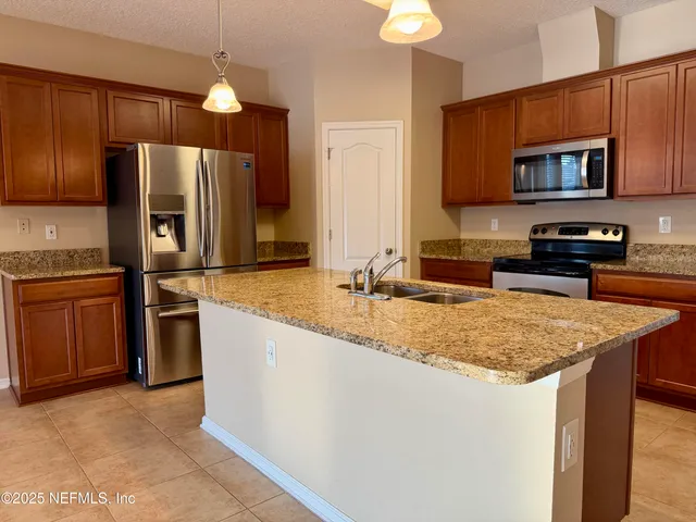 a kitchen with stainless steel appliances granite countertop a sink stove microwave and refrigerator