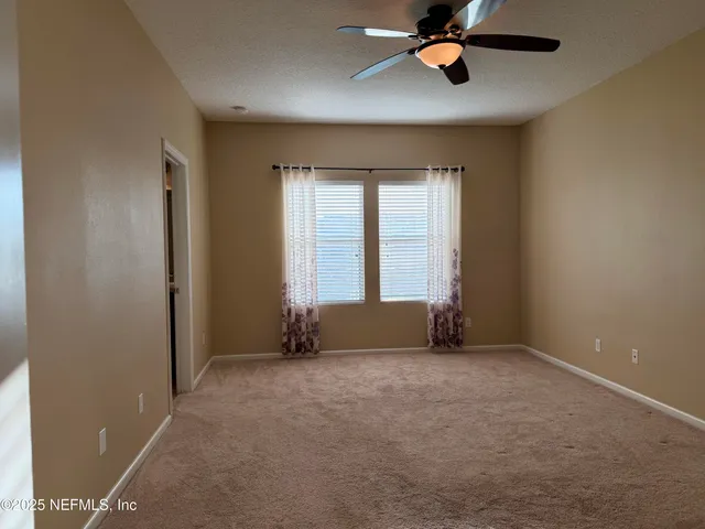 an empty room with windows and ceiling fan