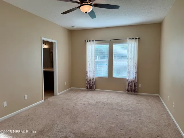 an empty room with windows and fan