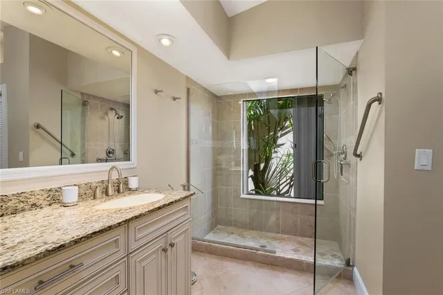 a bathroom with a granite countertop sink a mirror a vanity and a shower