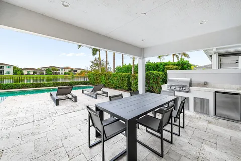 a kitchen with stainless steel appliances kitchen island granite countertop a stove a sink a dining table and chairs with white cabinets