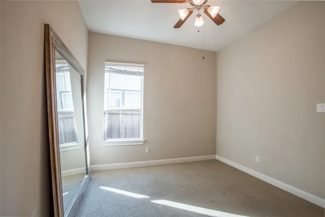 an empty room with windows and fan