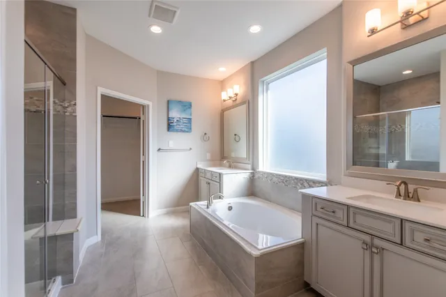 a bathroom with a bathtub a double vanity sink and mirror