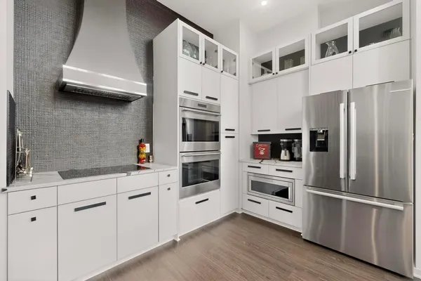 a kitchen with stainless steel appliances white cabinets and wooden floors