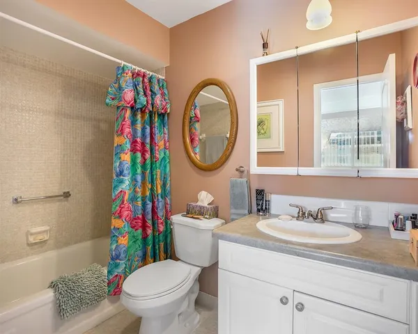 a bathroom with a toilet sink vanity tub and mirror