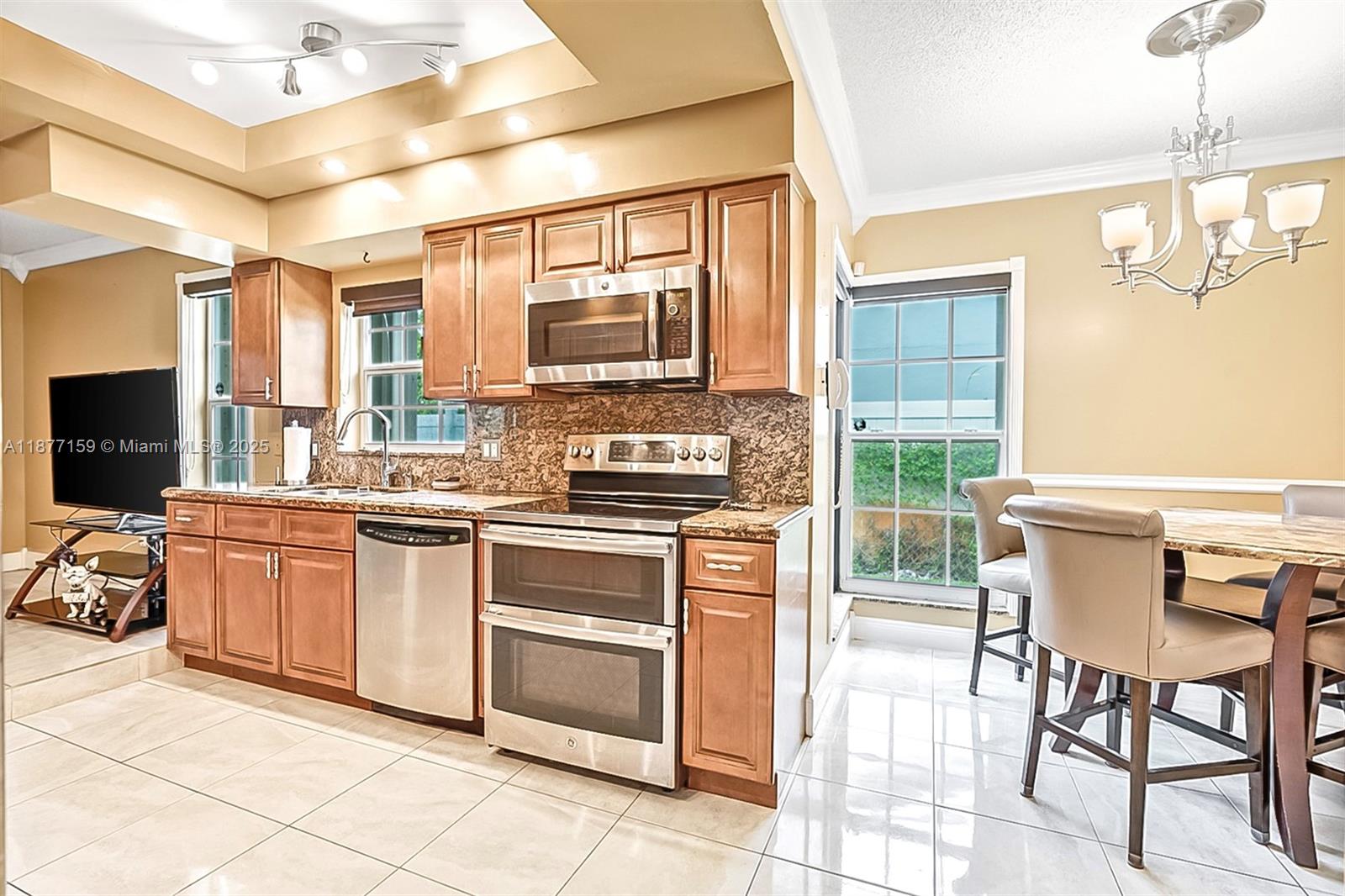 3568 Southwest 69th Way Miramar, FL 33023 - Photo 12 of 32 a kitchen with stainless steel appliances granite countertop a stove top oven a sink a dining table and chairs