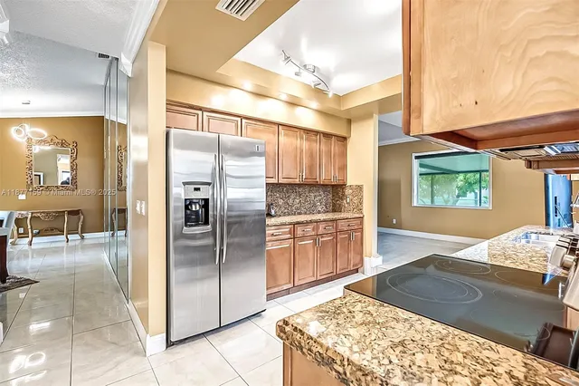 a kitchen with stainless steel appliances granite countertop a refrigerator a stove and a sink