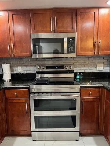 a kitchen with granite countertop a stove and a microwave