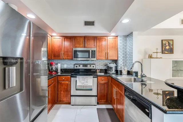 a kitchen with stainless steel appliances granite countertop a sink stove microwave and refrigerator