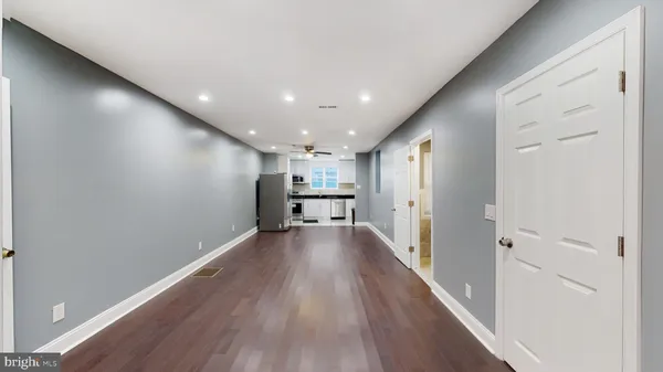 a view of an empty room with wooden floor and stairs
