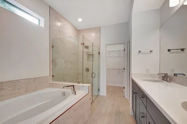 a bathroom with a tub sink shower and two mirror