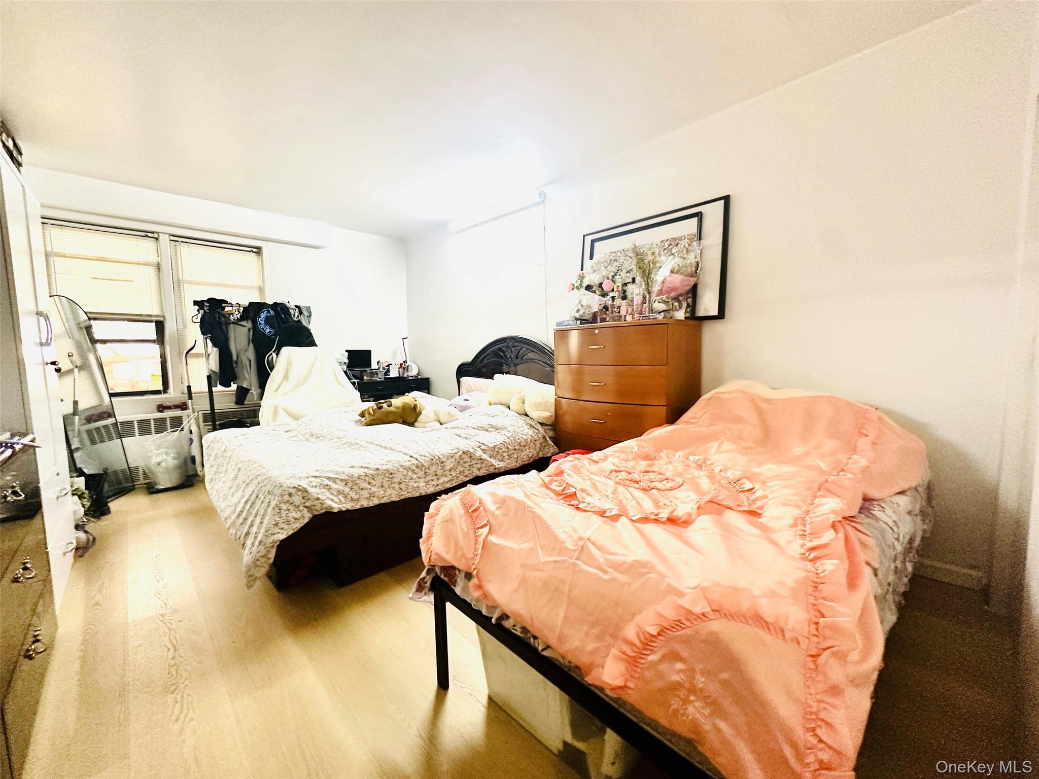 42-55 Colden Street, Unit 8N Queens, NY 11355 - Photo 4 of 7 a bedroom with two beds and a large mirror next to a window