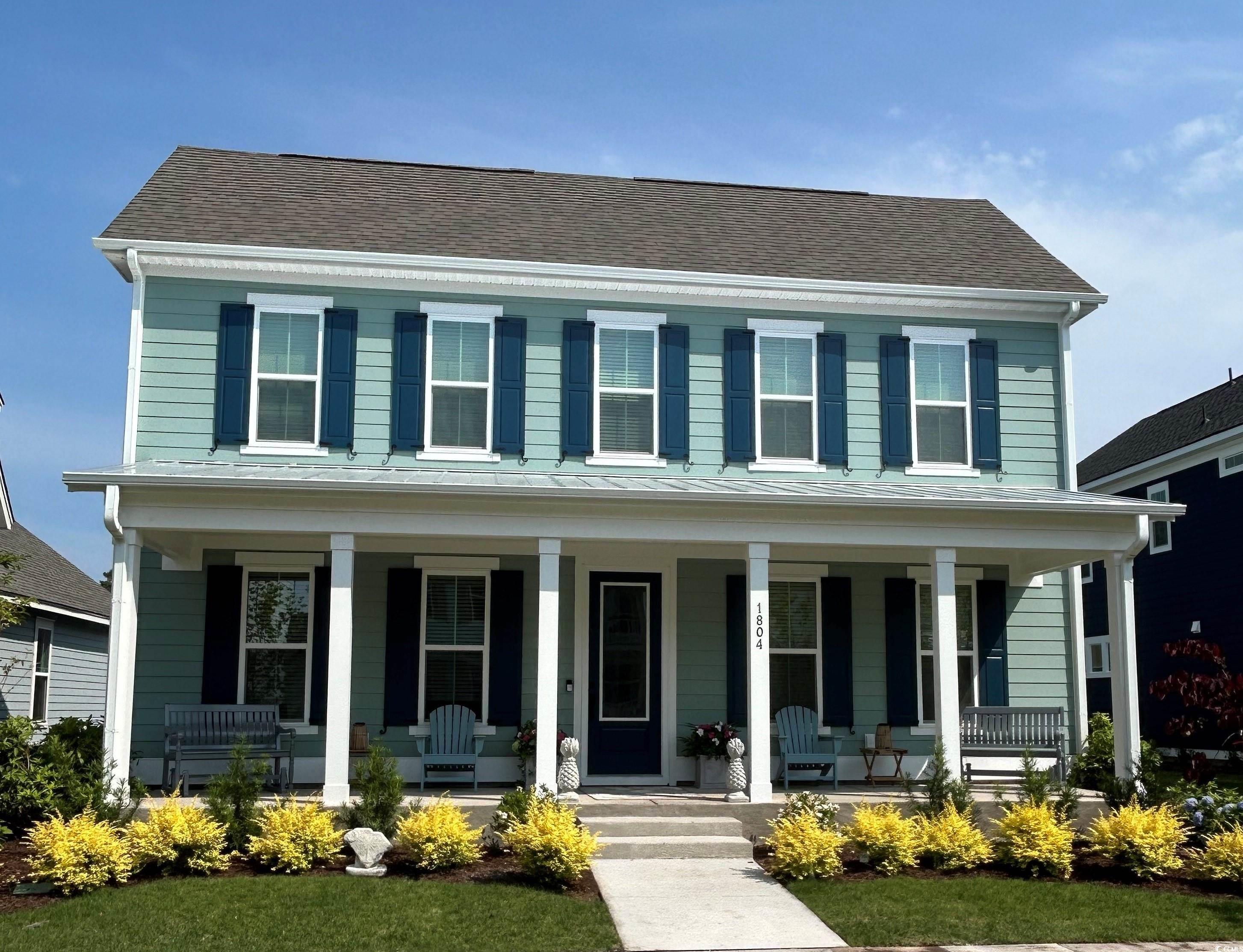 Colonial home featuring a porch and roof with shin