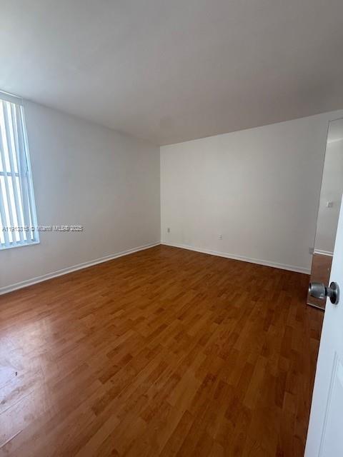 2350 Northeast 135th Street, Unit 711 North Miami, FL 33181 - Photo 7 of 10 an empty room with wooden floor and windows