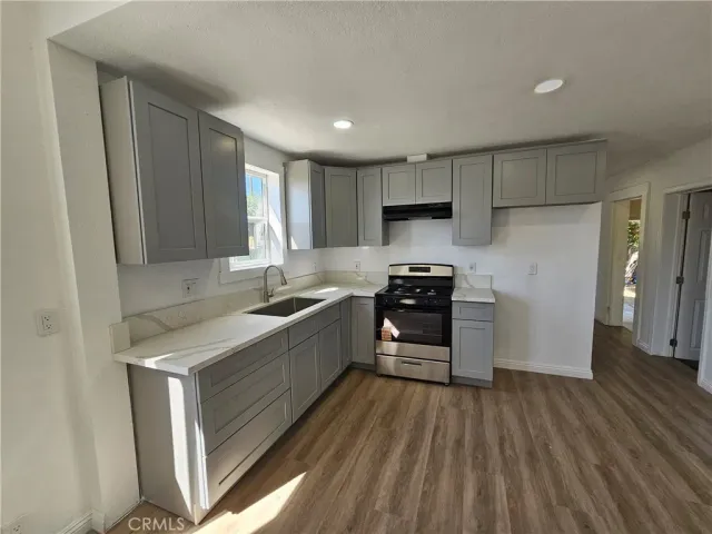 a kitchen with a refrigerator a stove top oven and wooden floor