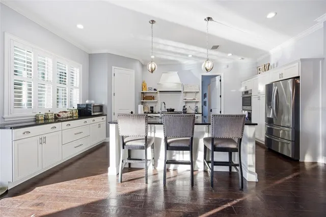 a kitchen with stainless steel appliances granite countertop a dining table chairs stove refrigerator and cabinets