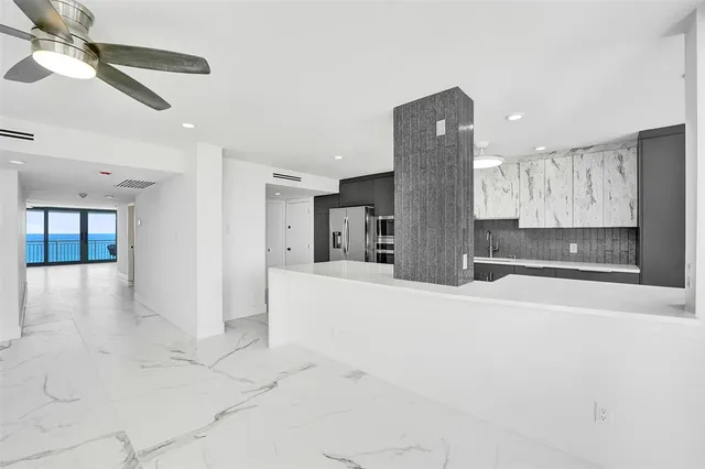 a large white kitchen with a large window appliances and furniture