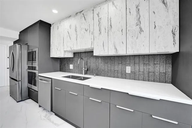 a large kitchen with granite countertop a sink stainless steel appliances and cabinets