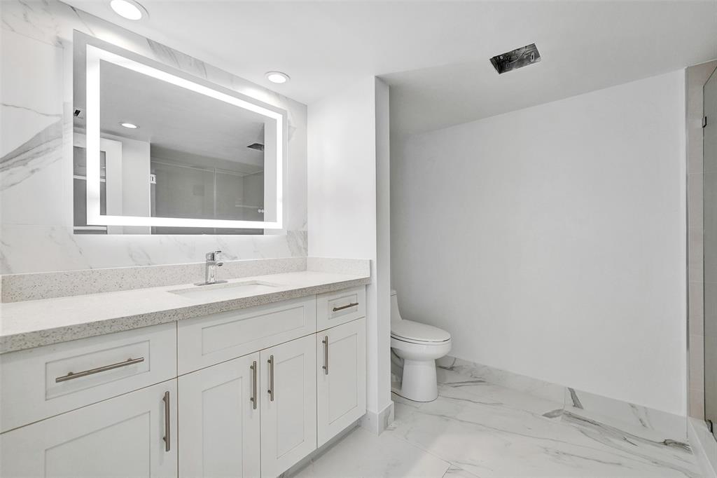 1390 South Ocean Boulevard, Unit 5C Pompano Beach, FL 33062 - Photo 25 of 35 a bathroom with a granite countertop sink a toilet and a mirror