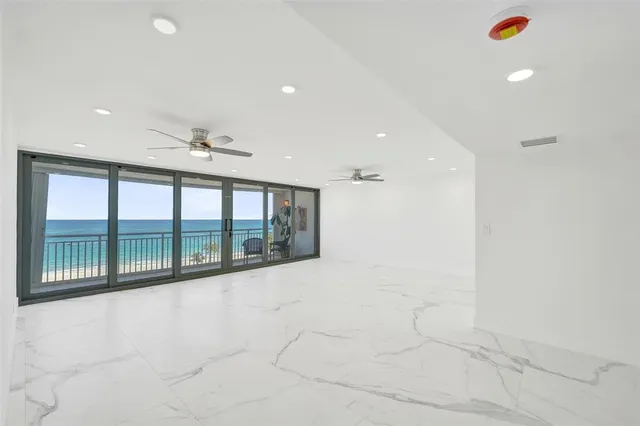 an empty room with chandelier fan and windows