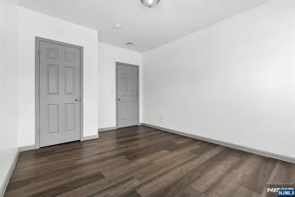 a view of an empty room with wooden floor and closet