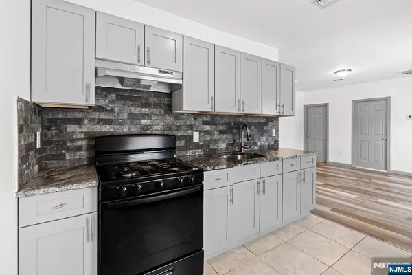 a kitchen with granite countertop white cabinets and stainless steel appliances