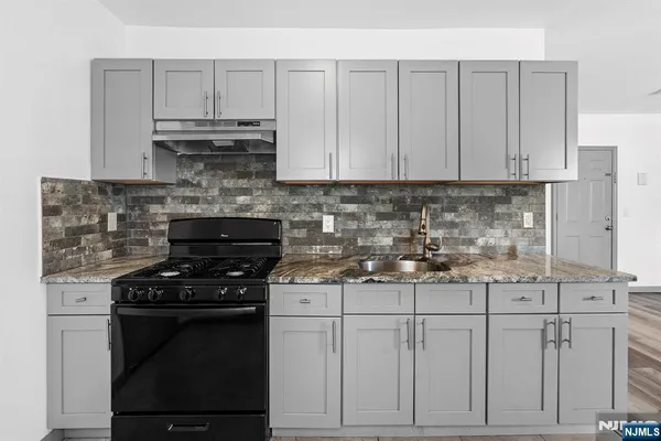a kitchen with stainless steel appliances granite countertop a stove a sink and white cabinets