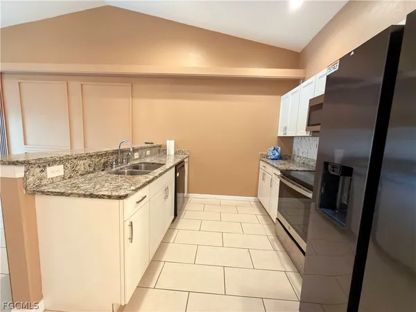 a kitchen with granite countertop a sink stove and cabinets