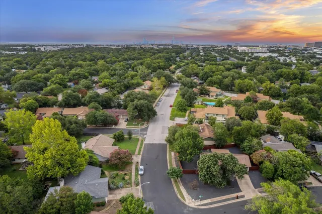 an aerial view of residential houses with outdoor space and trees