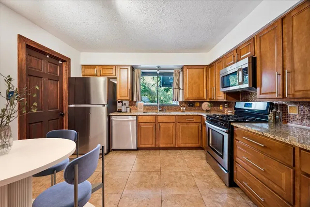 a kitchen with stainless steel appliances granite countertop a refrigerator stove microwave and sink
