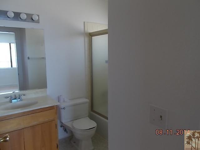 11522 Mesquite Avenue, Unit 2 Desert Hot Springs, CA 92240 - Photo 5 of 6 a bathroom with a toilet sink vanity and mirror