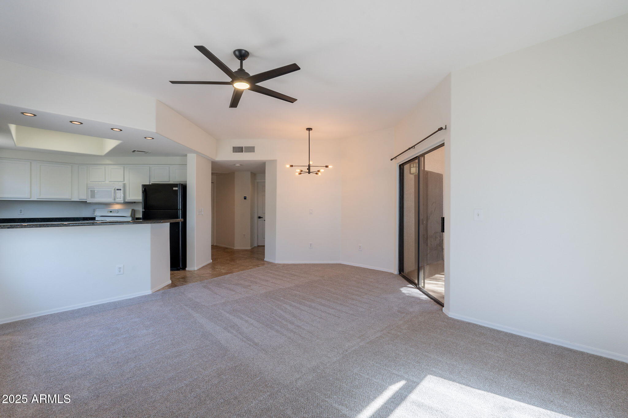 10030 West Indian School Road, Unit 218 Phoenix, AZ 85037 - Photo 8 of 28 a view of a livingroom with a ceiling fan & kitchen space