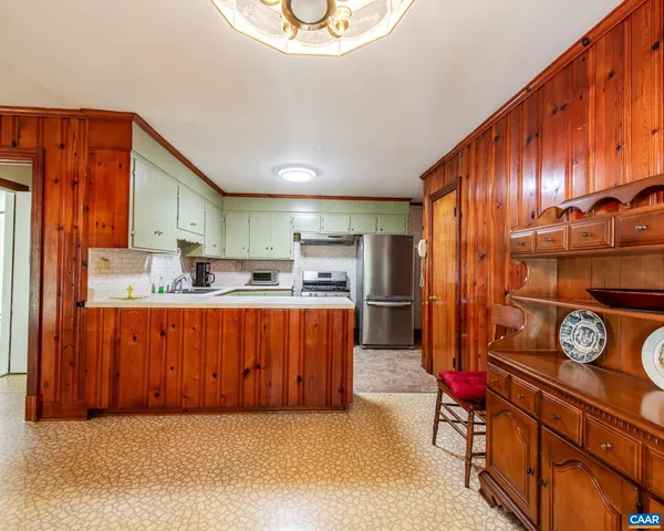 a kitchen with stainless steel appliances granite countertop a refrigerator a sink dishwasher a stove and a dining table with wooden floor