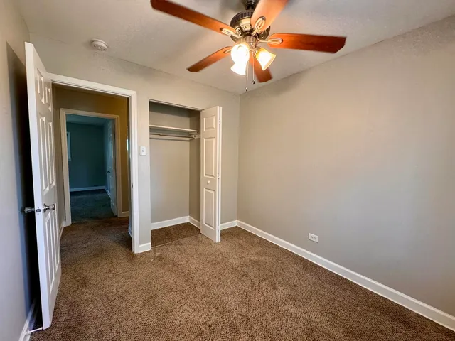an empty room with closet and a chandelier fan