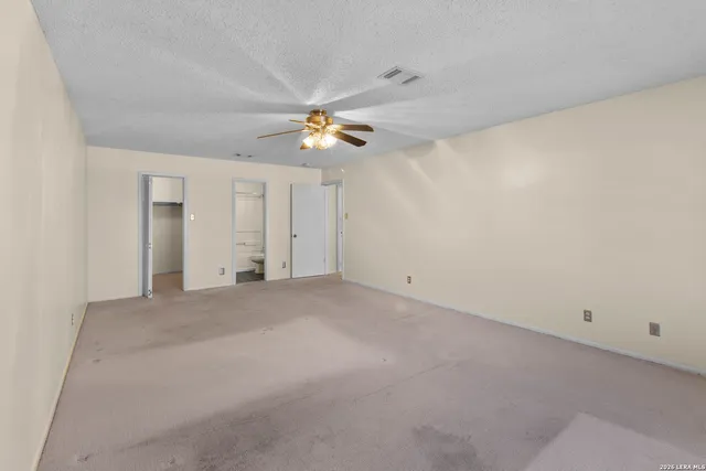an empty room with chandelier fan and windows