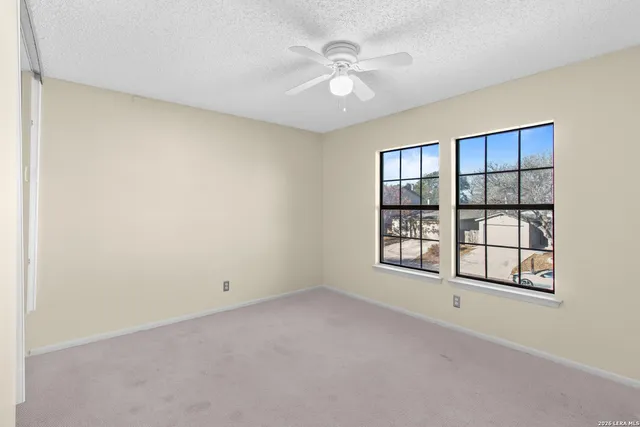 an empty room with windows and ceiling fan