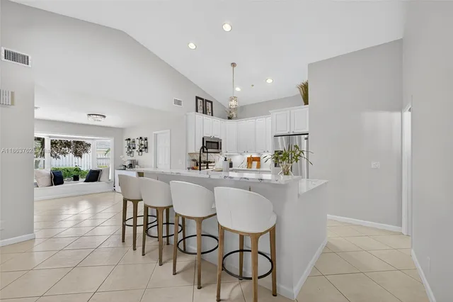 a spacious bedroom with a large bed a chandelier and windows