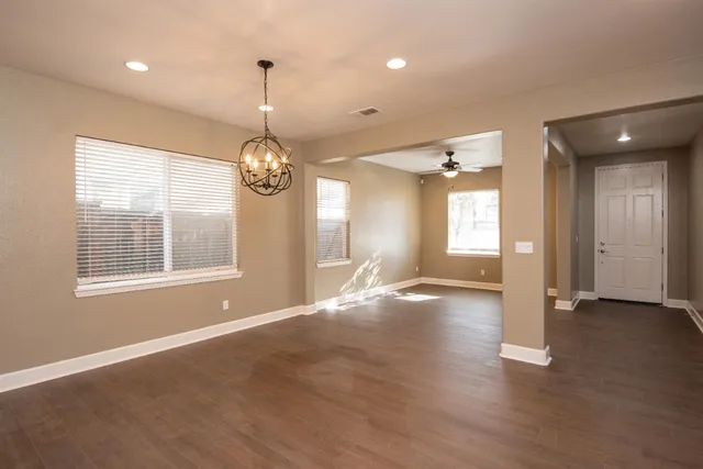 a view of an empty room with window and wooden floor