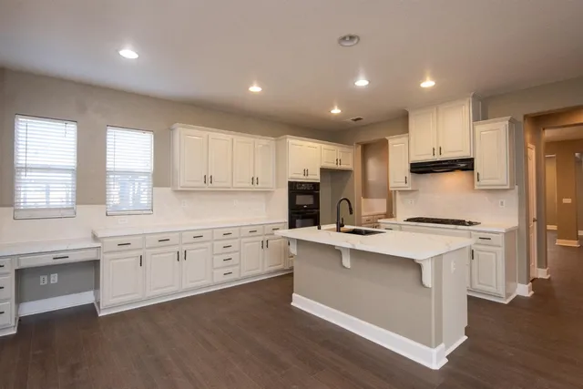 a kitchen with granite countertop a sink stove a refrigerator and cabinets