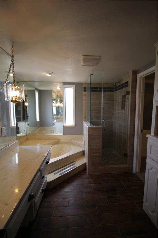 634 Ray Avenue DeSoto, TX 75115 - Photo 12 of 28 Bathroom featuring wood tiled floor, a shower stall, vanity, a bath, and a notable chandelier