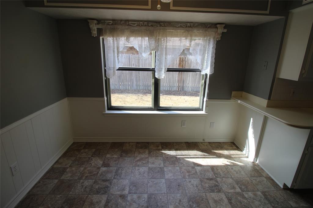 634 Ray Avenue DeSoto, TX 75115 - Photo 21 of 28 Unfurnished dining area featuring stone finish floor and a wainscoted wall