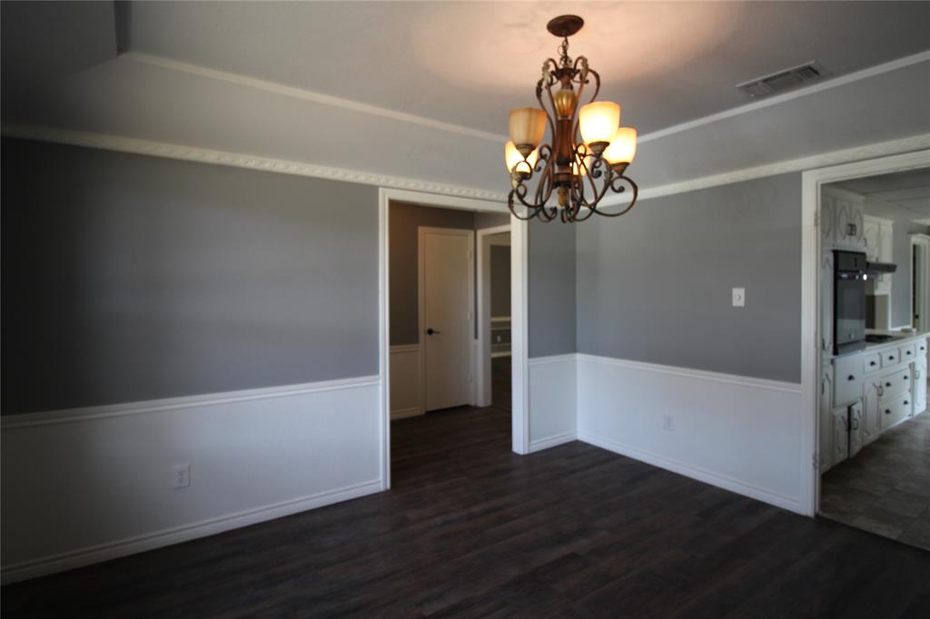 634 Ray Avenue DeSoto, TX 75115 - Photo 7 of 28 Unfurnished dining area featuring dark wood-type flooring, visible vents, baseboards, and an inviting chandelier