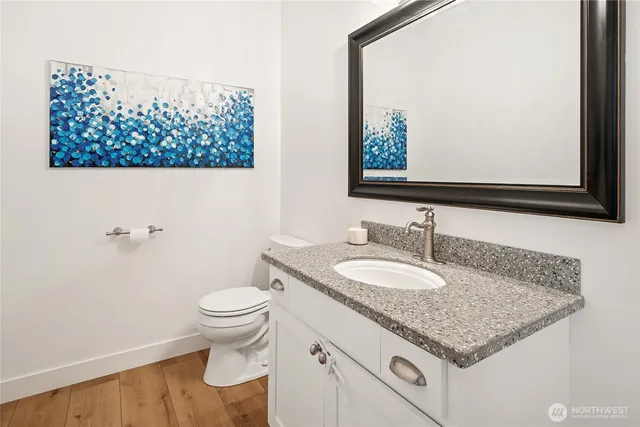 a bathroom with a granite countertop toilet a sink and a large mirror