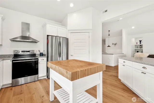 a kitchen with stainless steel appliances kitchen island granite countertop a refrigerator stove and sink