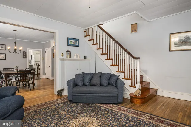 a living room with furniture and a dining table with wooden floor
